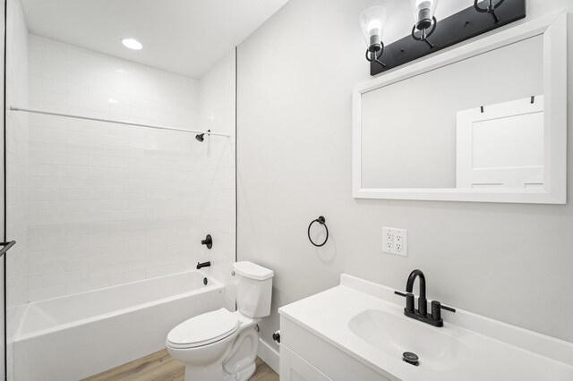 full bathroom with tiled shower / bath, vanity, toilet, and hardwood / wood-style floors