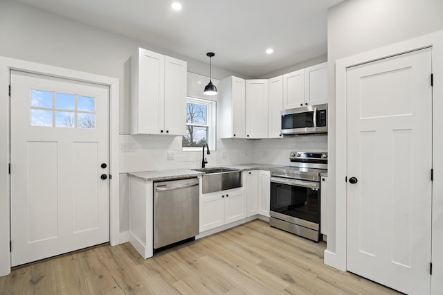 kitchen with pendant lighting, appliances with stainless steel finishes, sink, and white cabinets