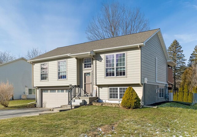 bi-level home featuring a garage and a front lawn