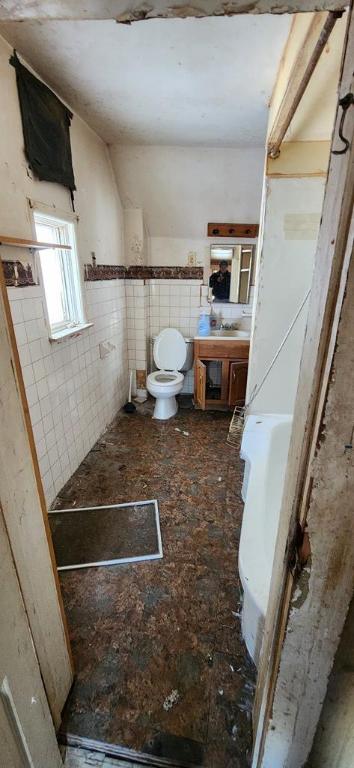 bathroom featuring toilet, sink, and tile walls