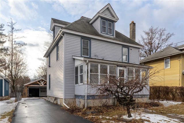 traditional style home featuring a garage, an outdoor structure, and a chimney