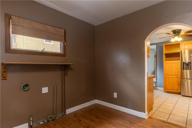 washroom featuring arched walkways, light wood-style flooring, a ceiling fan, and baseboards