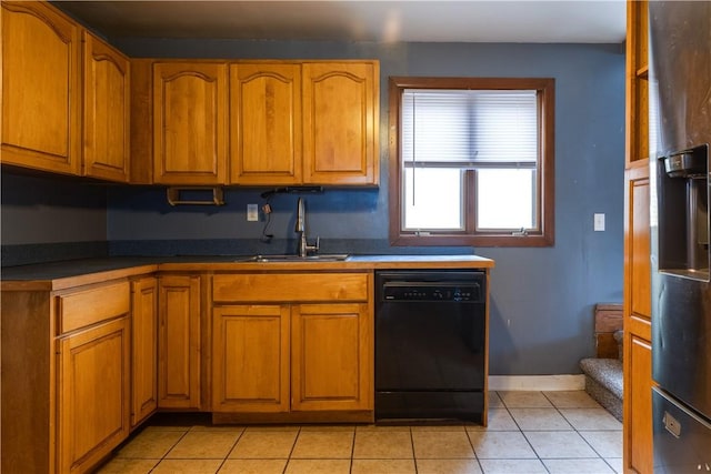 kitchen with black appliances, dark countertops, a sink, and brown cabinets