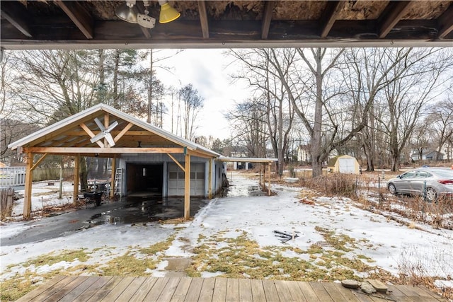 snow covered deck with a garage and an outdoor structure