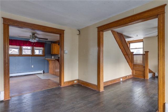 spare room featuring dark wood-style flooring, baseboards, stairway, and baseboard heating