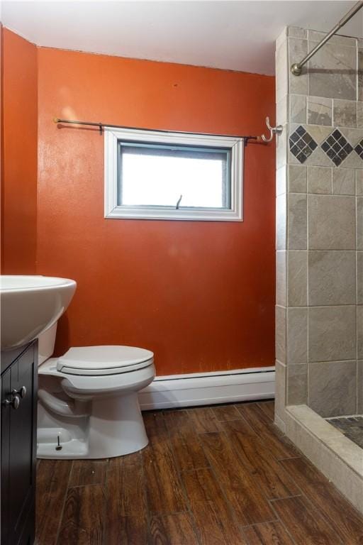 bathroom featuring toilet, a shower stall, baseboard heating, and wood finished floors