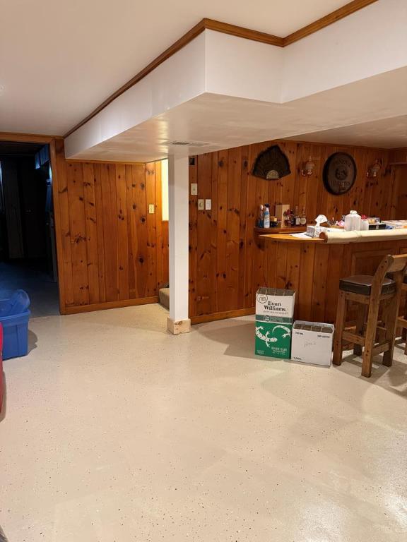 basement featuring wooden walls and bar area