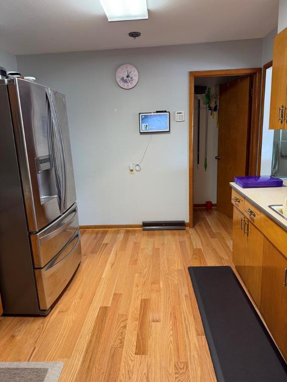 kitchen with stainless steel refrigerator with ice dispenser and light hardwood / wood-style flooring