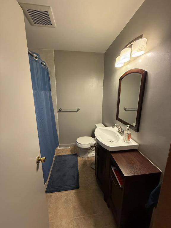 bathroom featuring vanity, curtained shower, tile patterned floors, and toilet