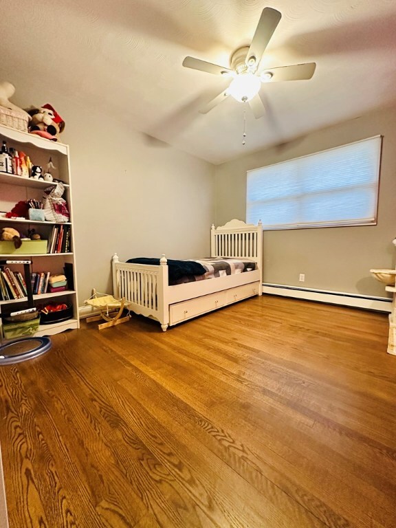 unfurnished bedroom featuring light wood-type flooring, ceiling fan, and baseboard heating