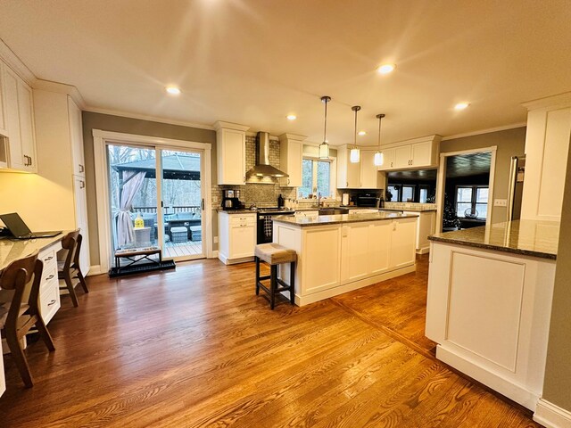 kitchen featuring pendant lighting, white cabinetry, a center island, dark wood-type flooring, and wall chimney exhaust hood