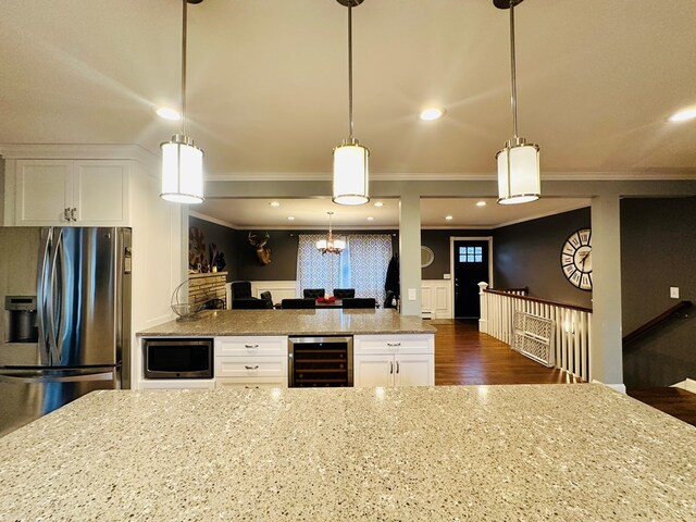 kitchen with pendant lighting, crown molding, appliances with stainless steel finishes, wine cooler, and white cabinets