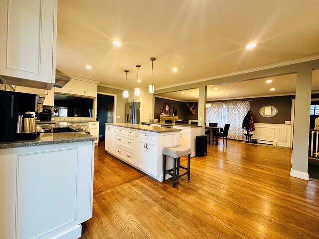 kitchen with a breakfast bar area, hanging light fixtures, a kitchen island, and white cabinets