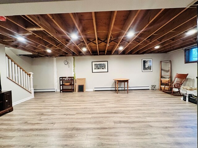 basement with a baseboard heating unit and light hardwood / wood-style flooring