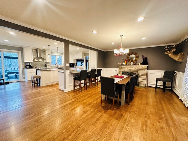 dining space with ornamental molding, a notable chandelier, and light wood-type flooring