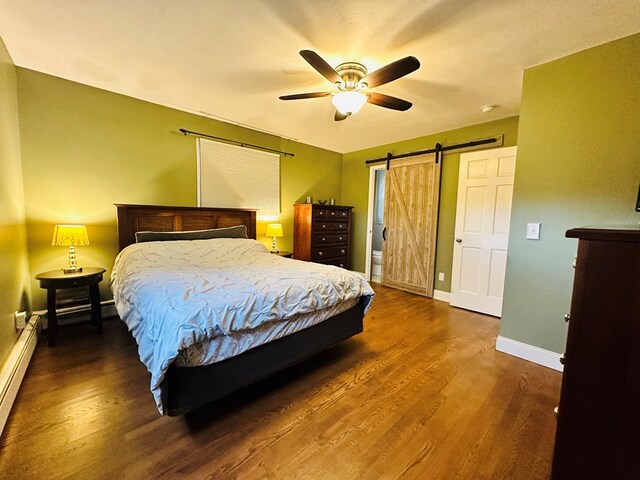 bedroom featuring a baseboard heating unit, dark hardwood / wood-style floors, a barn door, and ceiling fan