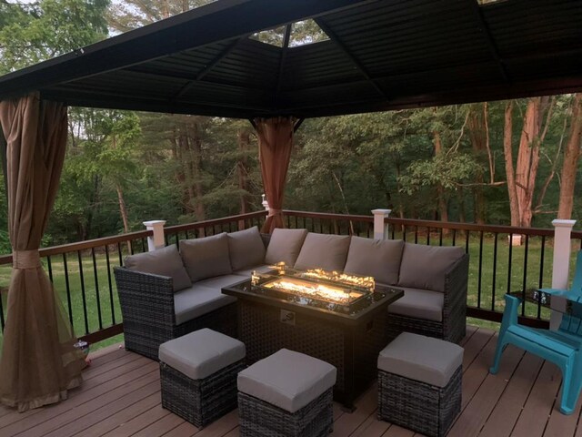 wooden terrace featuring an outdoor living space with a fire pit