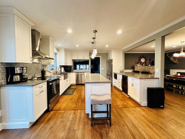 kitchen with wine cooler, white cabinets, appliances with stainless steel finishes, and wall chimney range hood