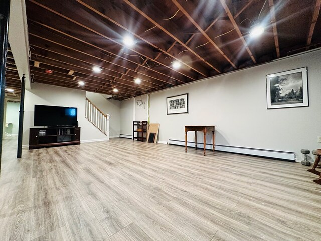 basement featuring hardwood / wood-style floors and a baseboard heating unit