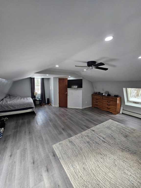 unfurnished bedroom with hardwood / wood-style flooring, vaulted ceiling, a baseboard heating unit, and ceiling fan