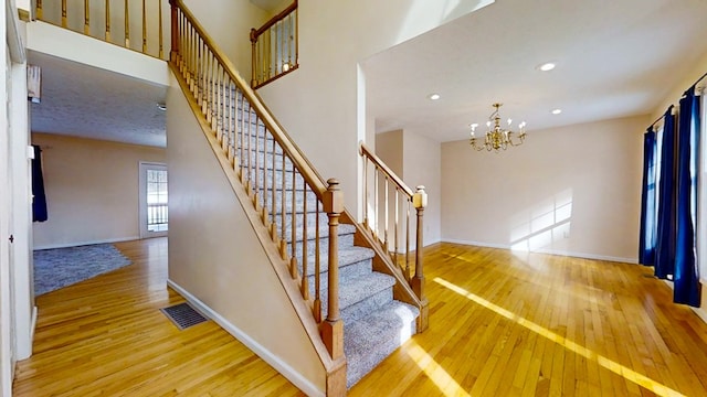 11827 Lando Ln, Corning, NY 14830 - stairs featuring hardwood / wood-style floors, a notable chandelier, and baseboards