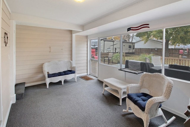 living area with wooden walls and dark colored carpet