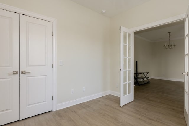 interior space with french doors, ornamental molding, a chandelier, and light hardwood / wood-style floors