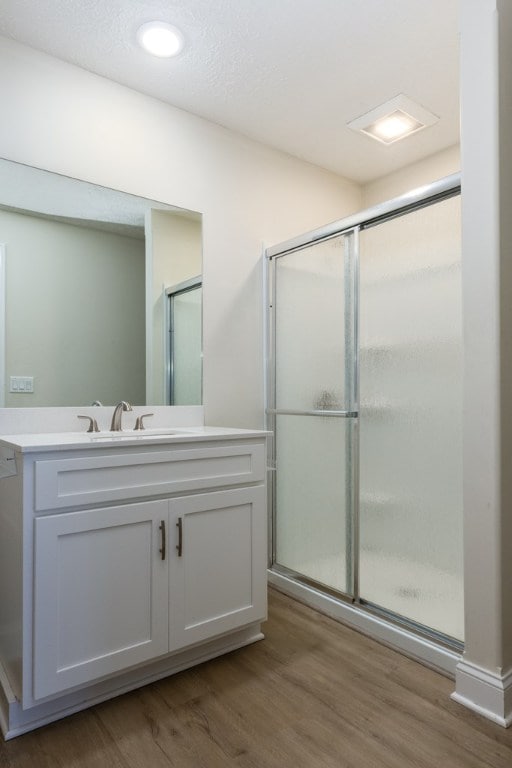 bathroom featuring hardwood / wood-style flooring, vanity, and a shower with door