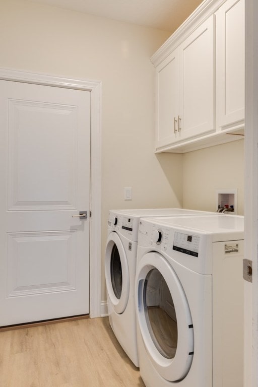 washroom featuring cabinets, washer and dryer, and light wood-type flooring