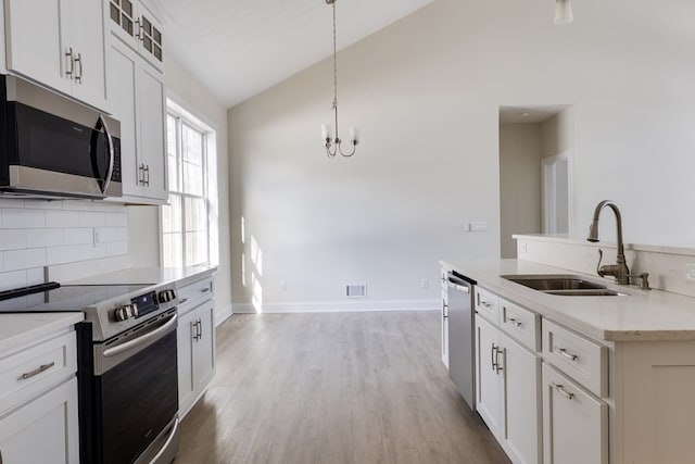 kitchen with sink, white cabinetry, hanging light fixtures, stainless steel appliances, and light stone countertops