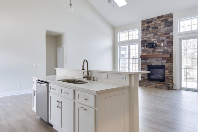 kitchen featuring sink, dishwasher, white cabinetry, a kitchen island with sink, and high vaulted ceiling