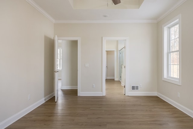 unfurnished bedroom featuring dark wood-type flooring, a tray ceiling, and crown molding