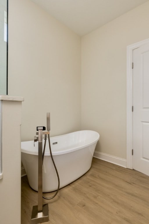 bathroom with hardwood / wood-style flooring and a tub to relax in