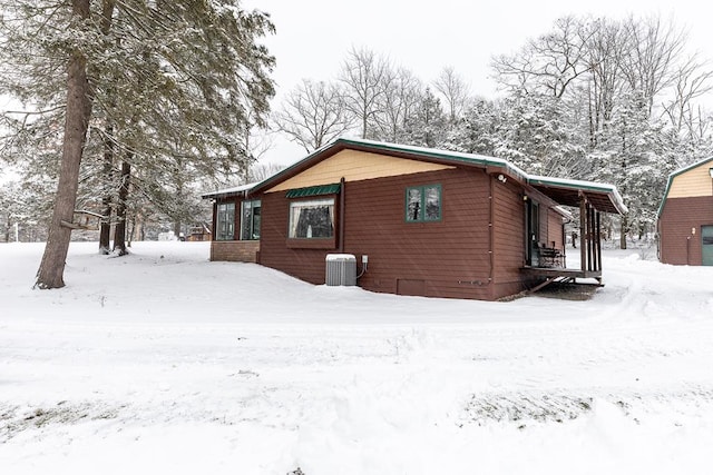 snow covered property with a porch and central AC unit