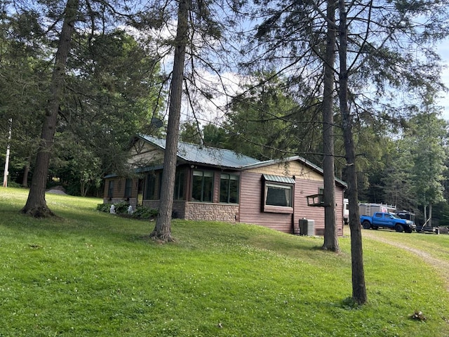 view of property exterior with central AC unit and a lawn