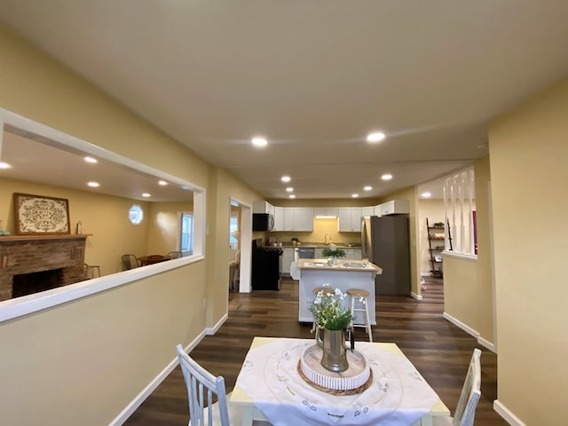 dining area featuring a fireplace, dark hardwood / wood-style flooring, and sink