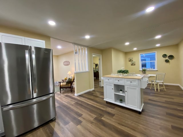 kitchen with white cabinetry, dark hardwood / wood-style floors, stainless steel fridge, and a kitchen island