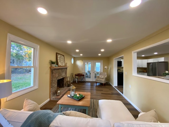 living room with a fireplace, dark hardwood / wood-style floors, a healthy amount of sunlight, and french doors