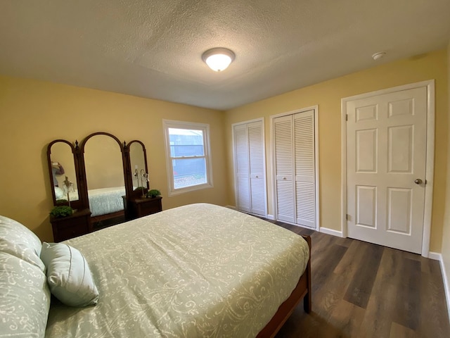 bedroom featuring multiple closets, dark hardwood / wood-style flooring, and a textured ceiling