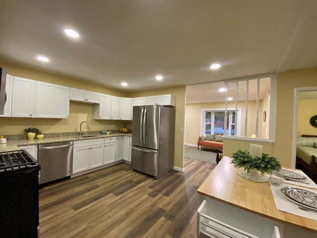 kitchen featuring appliances with stainless steel finishes, dark hardwood / wood-style floors, wood counters, sink, and white cabinets