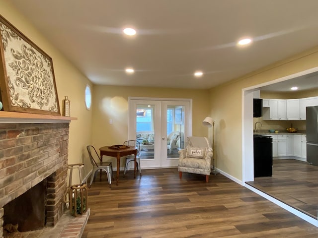 sitting room with french doors, dark hardwood / wood-style flooring, sink, and a brick fireplace