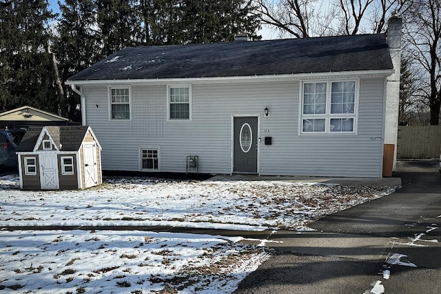 view of front of property with a storage unit, a chimney, and an outdoor structure