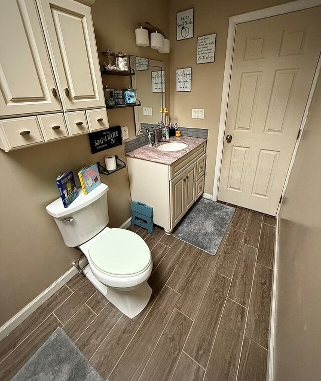 bathroom featuring wood tiled floor, toilet, vanity, and baseboards