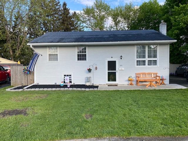 back of property featuring a patio area, a lawn, and a chimney