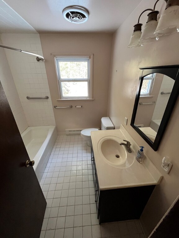 full bathroom featuring vanity, tiled shower / bath, and toilet