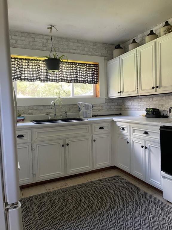 kitchen with sink, white cabinets, dark tile patterned flooring, decorative backsplash, and white refrigerator