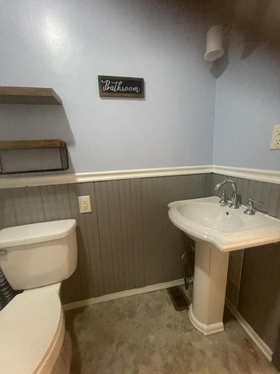 bathroom featuring wood walls and toilet