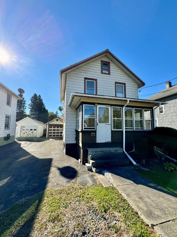 view of front of house featuring a garage and an outbuilding