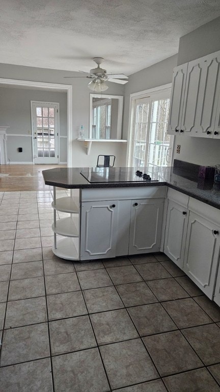 kitchen featuring white cabinetry, dark tile patterned flooring, kitchen peninsula, and a healthy amount of sunlight