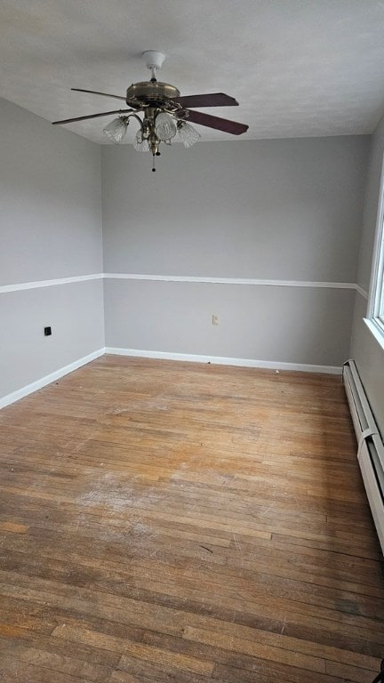 spare room featuring wood-type flooring and a baseboard heating unit